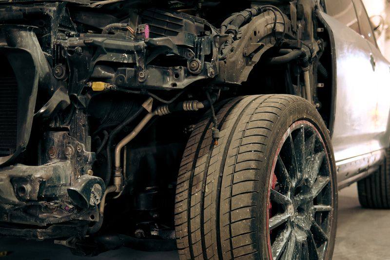 A Porsche Cayenne GTS with its front bodywork removed in a workshop, suspension and radiator exposed.