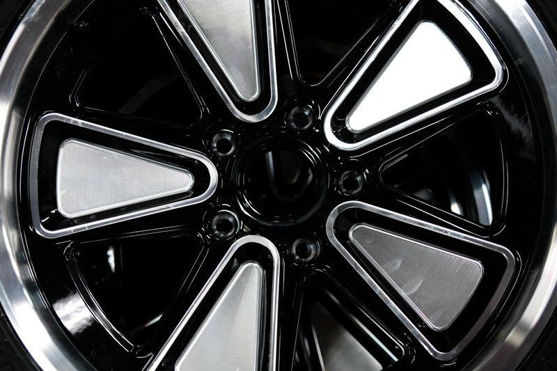 A five-spoke black wheel with a polished lip on an all-terrain tyre, for a Porsche Cayenne GTS.