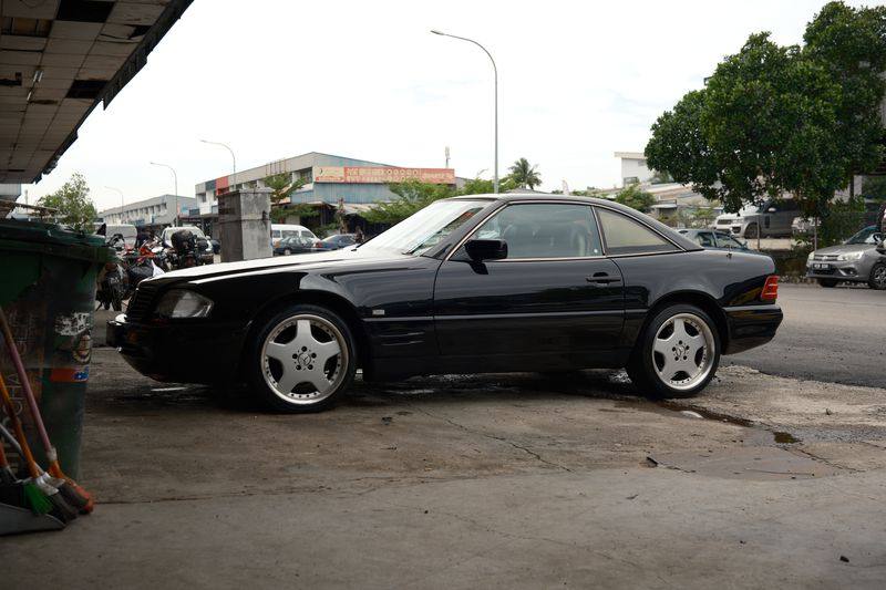 A closer profile view of the black R129 SL showing the door and wheel.