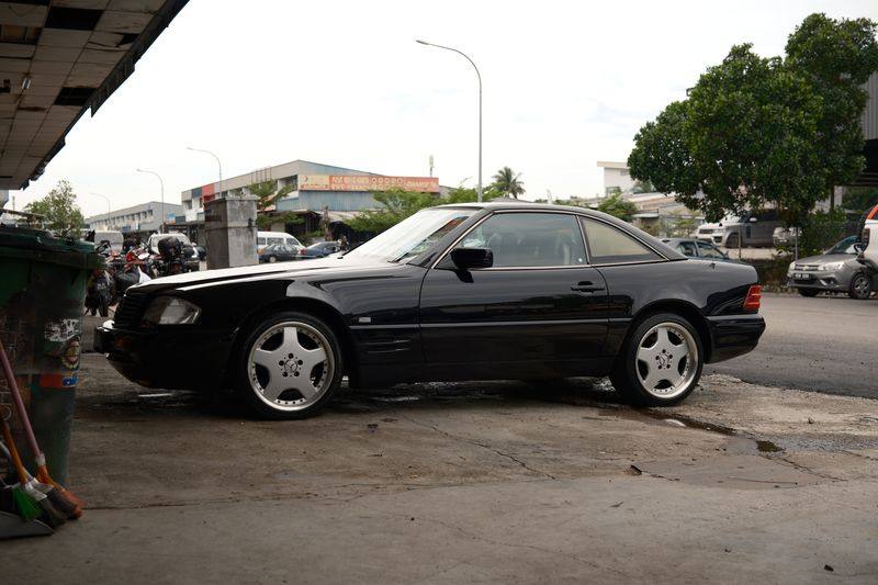 The same black R129 SL seen from the rear three-quarter.