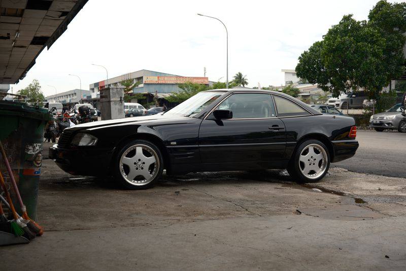 Close view of a five-spoke alloy wheel on the black R129 SL.