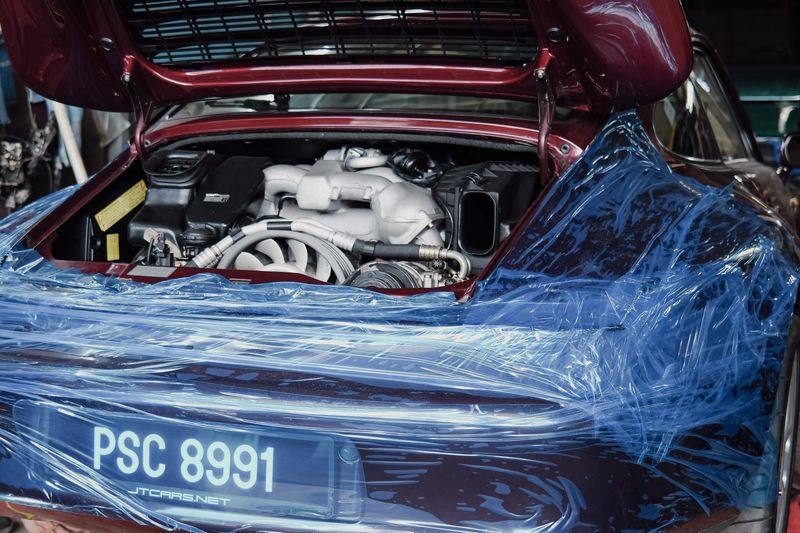 An Arena Red Porsche 911 Carrera 4S (993) in a workshop with its rear lid raised, from Project Tyrian.