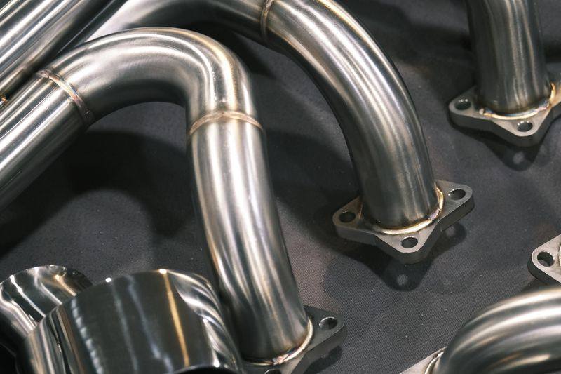 Close view of header runners meeting a flange, showing the weld and the bend radius.