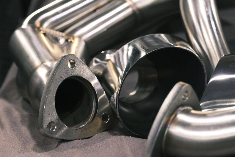 A three-bolt exhaust flange and cut pipe ends on a dark cloth.