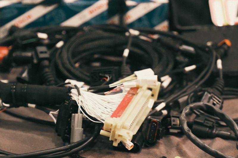 An engine wiring loom spread out, showing connector bodies and terminated wire bundles.