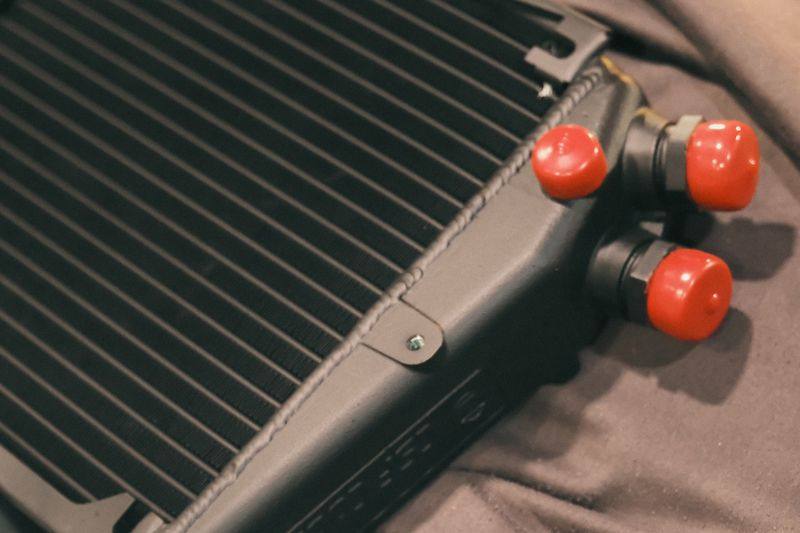 An oil cooler laid on a dark cloth among other replacement components.